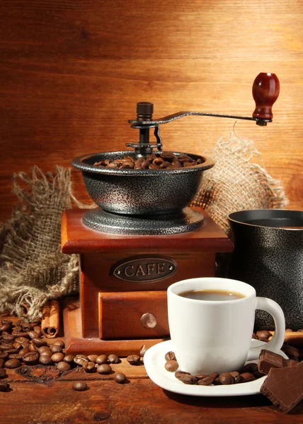 Koffiemolen, turk en kopje koffie op bruin houten achtergrond — Stockfoto