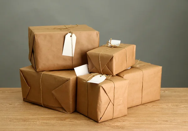 Cajas de paquetes con papel kraft, sobre mesa de madera sobre fondo gris —  Fotos de Stock
