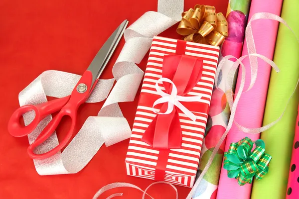 Rolos de papel de embrulho de Natal com fitas, arcos em fundo de cor — Fotografia de Stock