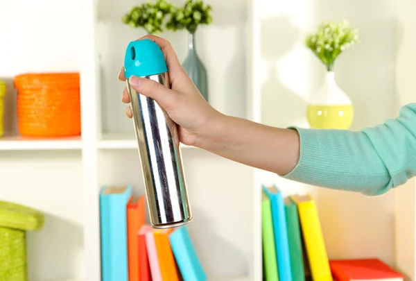 Sprayed air freshener in hand on white shelves background — Stock Photo, Image