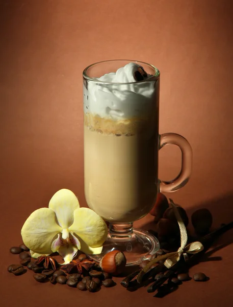 Fragrant coffee latte in glass cup with spices, on brown background — Stock Photo, Image