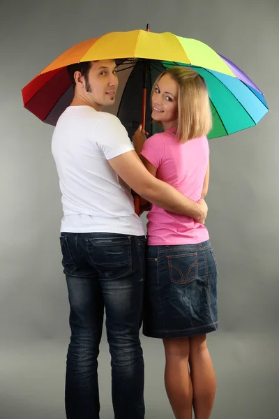 Casal amoroso com guarda-chuva no fundo cinza — Fotografia de Stock