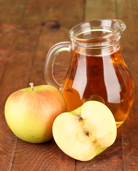 Pleine cruche de jus de pomme et de pomme sur fond en bois — Photo