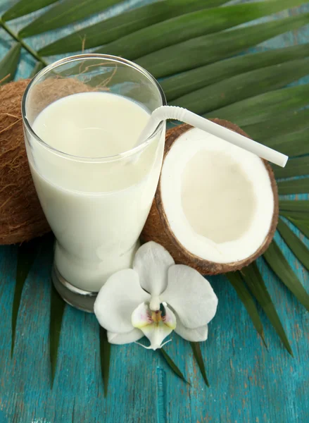 Cocos con vaso de leche, sobre fondo azul de madera —  Fotos de Stock