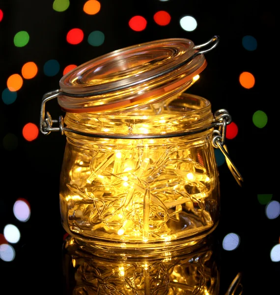 Kerstverlichting in glazen fles op wazig lichten achtergrond — Stockfoto