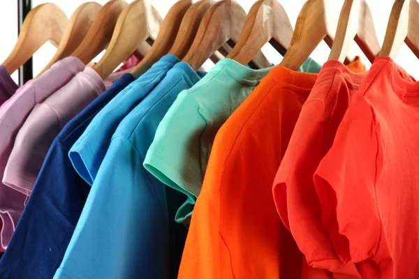 Wybór ubrań o różnych kolorach na drewniane wieszaki, na białym tle — Zdjęcie stockowe