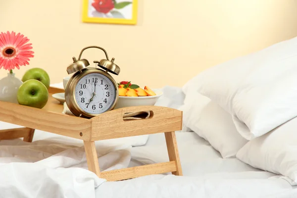 Träbricka med lätt frukost på sängen — Stockfoto