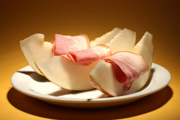 Parma ham and melon, on yellow background — Stock Photo, Image