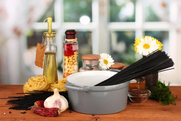明るい背景に木製のテーブルの上の鍋にスパゲティ — ストック写真