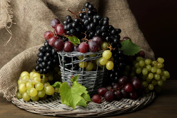 Sortimento de uvas doces maduras em cesta, sobre fundo marrom — Fotografia de Stock