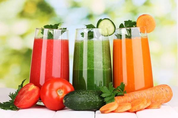 Fresh vegetable juices on wooden table, on green background — Stock Photo, Image