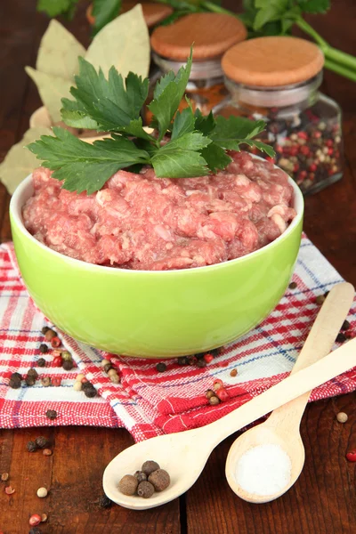 Bowl of raw ground meat with spices on wooden table — Stock Photo, Image