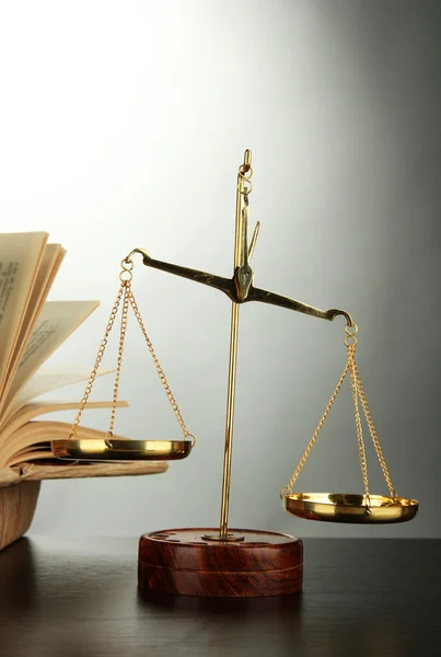 Gouden schalen van Justitie en boeken over de grijze achtergrond — Stockfoto
