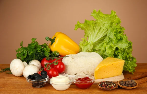 Ingredienser för pizza på träbord på brun bakgrund — Stockfoto