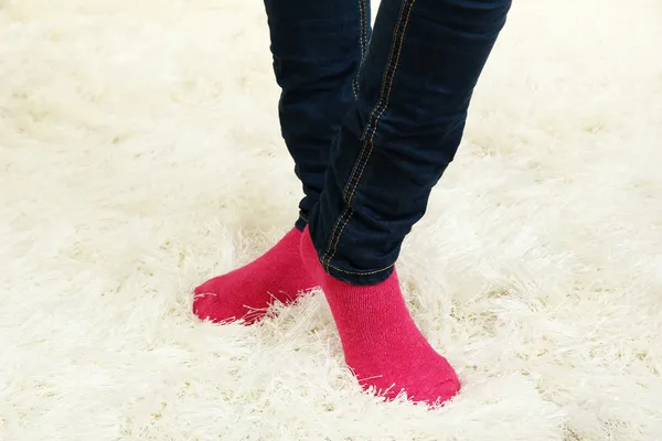 Женские ноги в разноцветных носках на белом фоне ковра — стоковое фото
