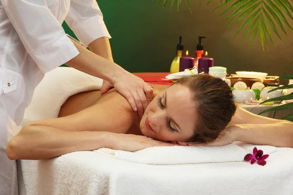 Bela mulher no salão de spa com pedras recebendo massagem, no fundo verde — Fotografia de Stock
