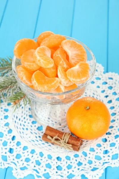 Sabrosas rebanadas de mandarina en tazón de vidrio sobre fondo azul —  Fotos de Stock