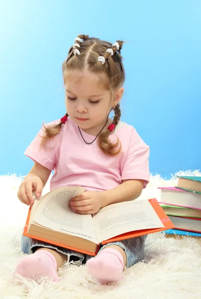 Schattig klein meisje met kleurrijke boeken, op blauwe achtergrond — Stockfoto