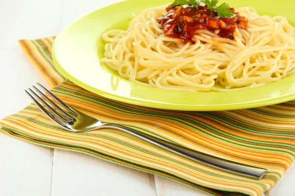 Italské špagety v talíři na dřevěném stole — Stock fotografie