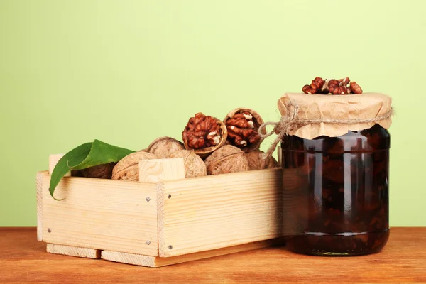 Mermelada-tarro de nueces y caja de madera sobre fondo verde — Foto de Stock