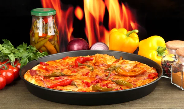 Tasty pepperoni pizza in pan with vegetables on flame background — Stock Photo, Image