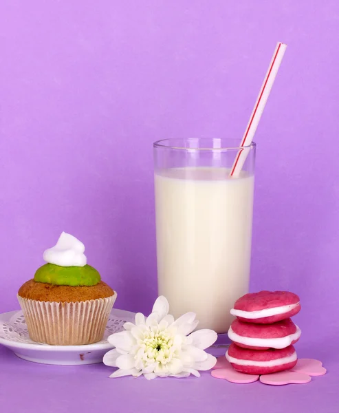 Glass of fresh new milk with cakes on purple background — Stock Photo, Image