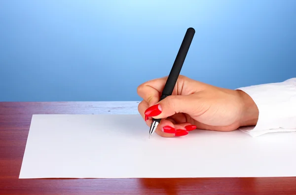 Manos escribiendo sobre papel sobre fondo azul —  Fotos de Stock