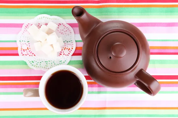 Vista superior de la taza de té y tetera en manteles coloridos — Foto de Stock