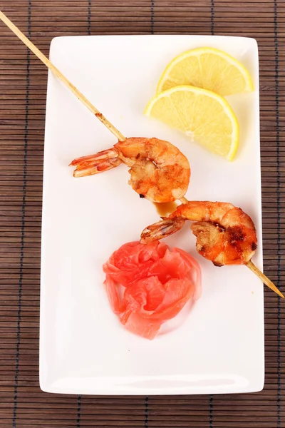 Shrimp skewers on plate with ginger and lemon — Stock Photo, Image