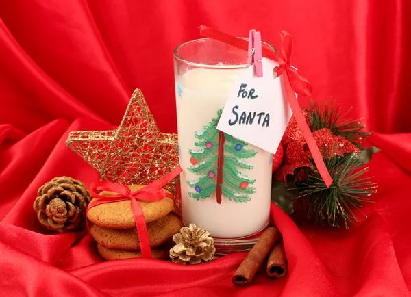 Cookies voor santa: Conceptuele afbeelding van gember koekjes, melk en kerst decoratie op rode achtergrond — Stockfoto