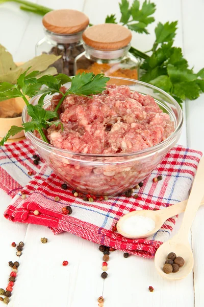 Bowl of raw ground meat with spices on wooden table Stock Picture