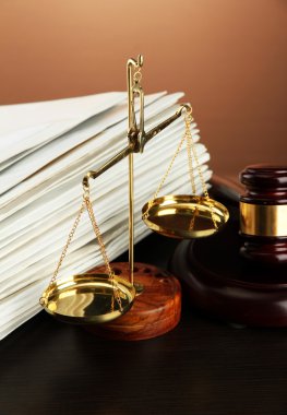 Golden scales of justice, gavel and folders on brown background clipart