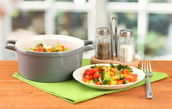 Ragoût de légumes en pot gris sur table en bois sur fond lumineux — Photo