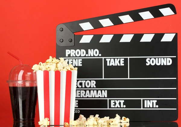 Film clapperboard, cola i popcorn na czerwonym tle — Zdjęcie stockowe