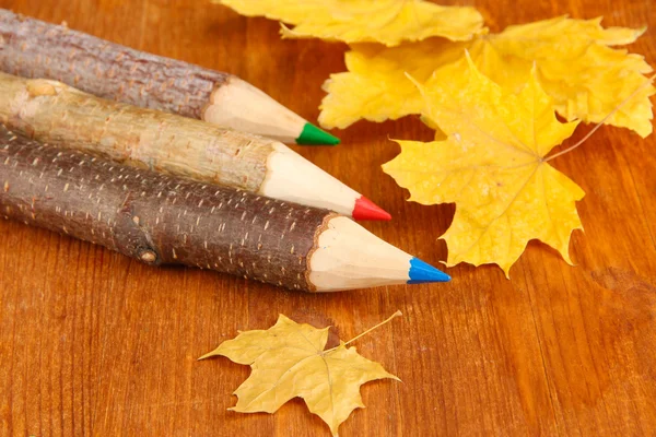 Kleurrijke houten potloden met herfst bladeren op houten tafel — Stockfoto