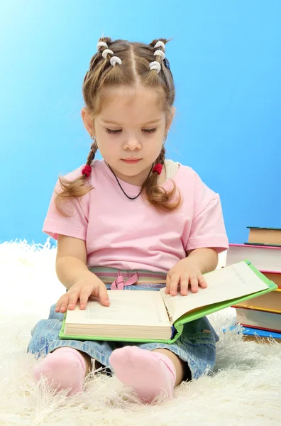 Menina bonito com livros coloridos, no fundo azul — Fotografia de Stock