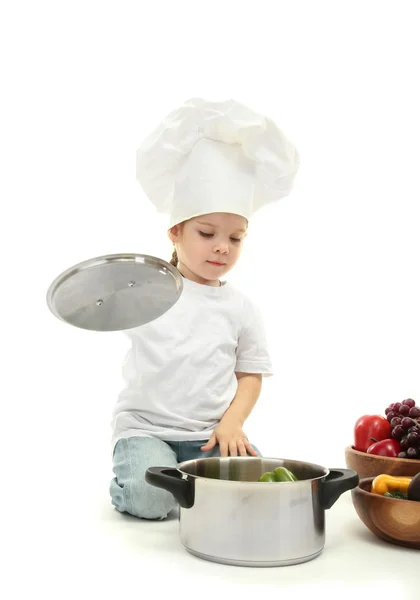 Kleines Mädchen in Kochmütze mit Pfanne und Gemüse, isoliert auf weiß — Stockfoto