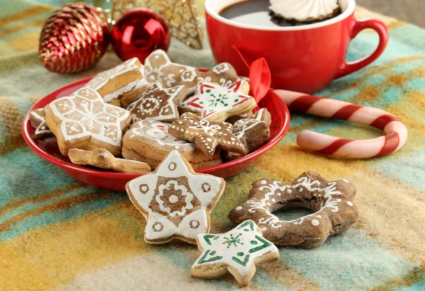 Christmas treats on plate and cup of coffe on plaid close-up — Stock Photo, Image