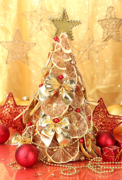 Schöner Weihnachtsbaum aus trockenen Zitronen mit Dekor, auf gelbem Hintergrund — Stockfoto