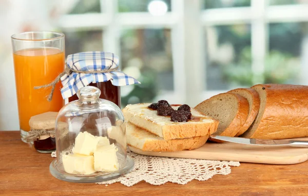 Masło na szkło talerzyk z szklaną pokrywę i świeży chleb, dżem na jasnym tle — Zdjęcie stockowe