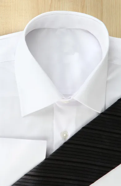 New white man 's shirt with color tie on wooden background — стоковое фото