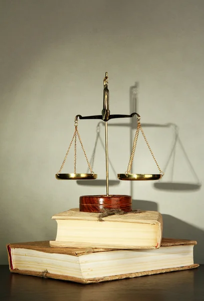 Gold scales of justice and books on grey background — Stock Photo, Image