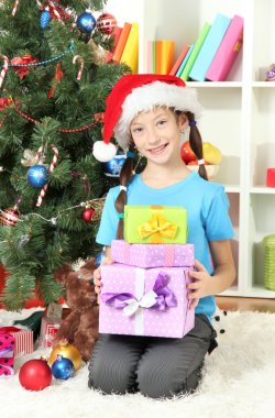Hediyelik kutu Noel ağacının yakınında tutan küçük bir kız