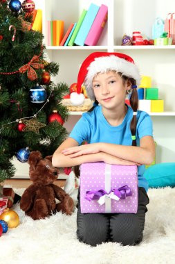 hediye kutusu Noel ağacının yakınında tutan küçük bir kız