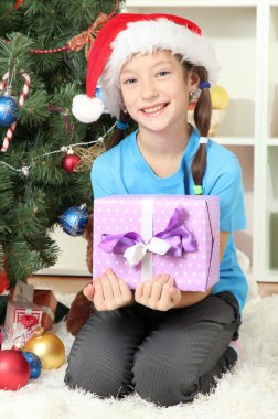 hediye kutusu Noel ağacının yakınında tutan küçük bir kız