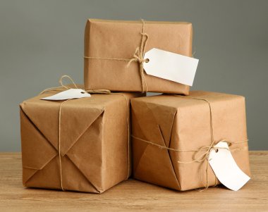 parcels boxes with kraft paper, on wooden table on grey background clipart