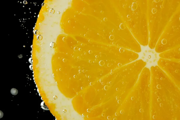 Rebanada de naranja en el agua con burbujas, sobre fondo negro —  Fotos de Stock