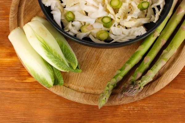 Сковородка с капустным салатом, спаржа и цикорий на фоне деревянного стола — стоковое фото