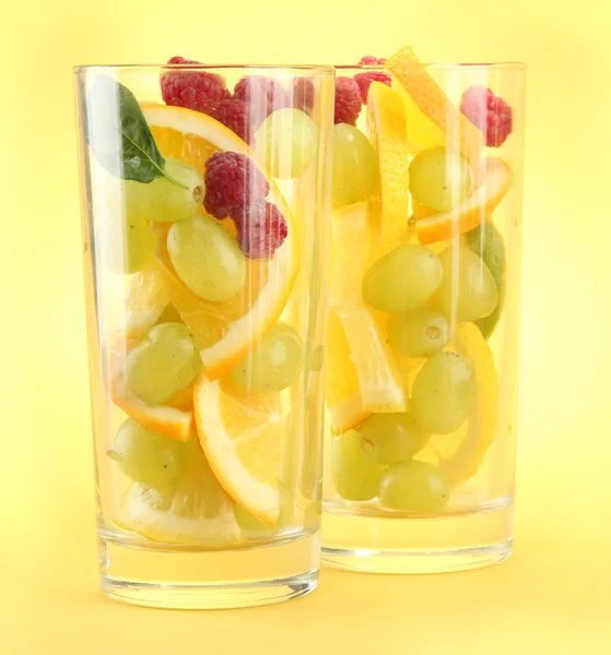 Transparent glas med citrusfrukter, på gul bakgrund — Stockfoto