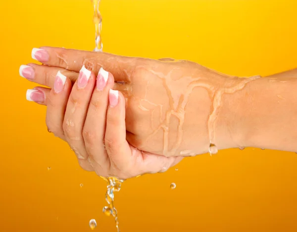Миття рук жінки на помаранчевому фоні крупним планом — стокове фото